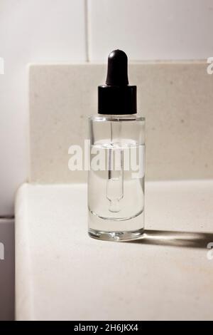 Glasbehälter mit kosmetischer Säurepipette auf der Oberseite des Badezimmerschranks, Hautpipettenbehälter auf der Waschtischeinheit des Badezimmers Stockfoto