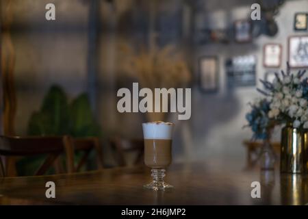 Glastasse mit Latte steht auf dem Tisch im Café. Glas mit Karamell-Cappuccino auf dem Tisch im Restaurant. Foto für das Menü, Werbung Stockfoto
