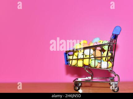 Bunte ostereier in einem Warenkorb auf dem rosa Hintergrund. Ostern ist ein christlicher Feiertag, der den Glauben an die Auferstehung von feiert Stockfoto