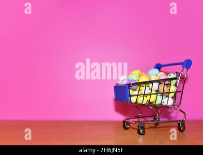 Bunte ostereier in einem Warenkorb auf dem rosa Hintergrund. Ostern ist ein christlicher Feiertag, der den Glauben an die Auferstehung von feiert Stockfoto