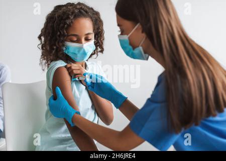 Medizinische Arbeiter Tragen Gesichtsmaske Impfung African Girl In Der Klinik Stockfoto