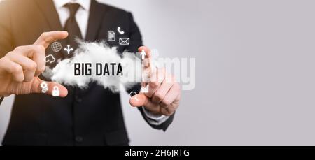 Geschäftsmann hält die Inschrift , Wort BIG DATA . Vorhängeschloss, Gehirn, Mann, Planet, Graph, Lupe, Zahnräder, Symbol für Cloud, Grid, Dokument, Brief, Telefon Stockfoto