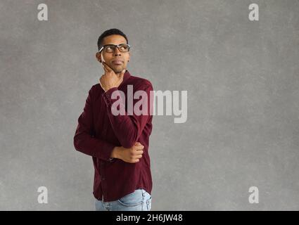 Studioporträt eines nachdenklichen Mannes, der das Kinn berührt und Schulter an Seite blickt Stockfoto