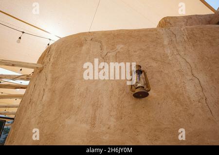 Typische arabische Öllampe oder Laterne, die an der Grunge-Wand des alten Gebäudes hängt. Details der alten Innenräume des Nahen Ostens. Al Fahidi Historical Neighborhood, Dubai Stockfoto