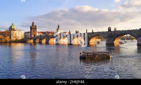 Ansicht der historischen Karlsbrücke, die die Moldau überquert, in Prag, Tschechische Republik. Old Town Bridge Tower und ein Kreuzschiff sichtbar. Stockfoto