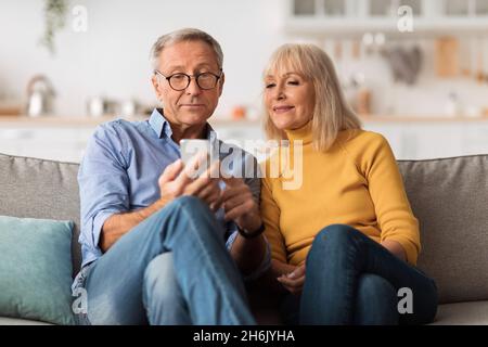 Ehemann Und Ehefrau Mit Smartphone Zu Hause Stockfoto