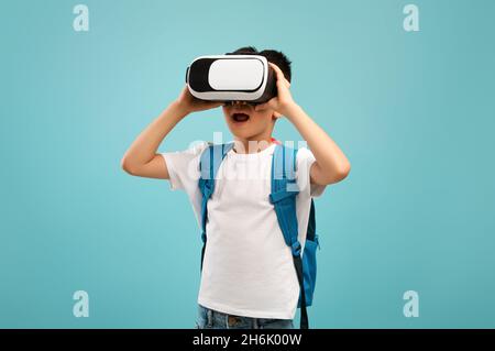 Porträt eines aufgeregten kleinen asiatischen Schuljungen, der virtuelle Realität in einer VR-Brille erlebt Stockfoto