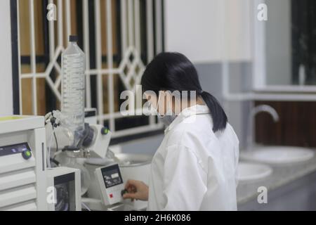 Vietnamesische Wissenschaftlerin, die einen Rotationsverdampfer bediente, um ein Experiment im Labor zu machen Stockfoto