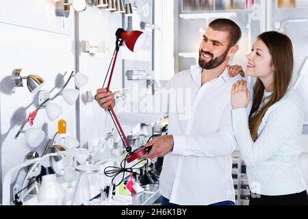 Positive Familie Kauf versucht Tischleuchte im modernen Möbelgeschäft Stockfoto