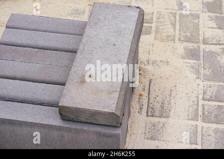 Der Stapel der Bordsteine auf den Steinfliesen mit dem Sand. Stockfoto