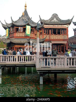 Shanghai, China: Das Huxinting Teehaus in der Altstadt von Shanghai. Die Menschen gehen über die Zick-Zack-Brücke über einen kleinen See in der Nähe der Yu-Gärten. Stockfoto