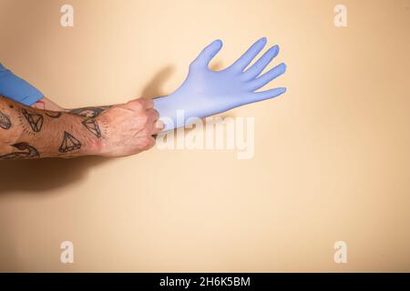 Verkürzte Hände Einer Person, Die Op-Handschuhe Gegen Hellen Hintergrund Aufsetzt Stockfoto