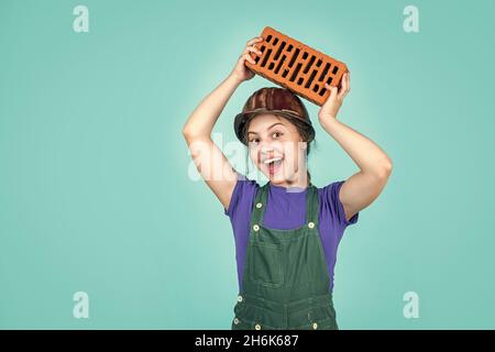 Fröhliche Kinderarbeiter mit Gebäude Uniform und Ziegel, Gebäude Stockfoto