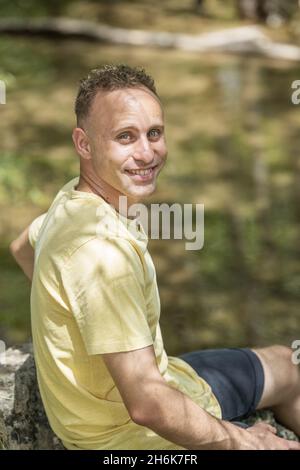 Junger Mann im gelben Hemd im Park mit dem verschwommenen Hintergrund Stockfoto