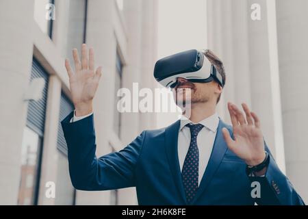 Geschäftsmann in einer Virtual-Reality-Brille mit VR-Brille, während er auf der Stadtstraße im Freien steht Stockfoto