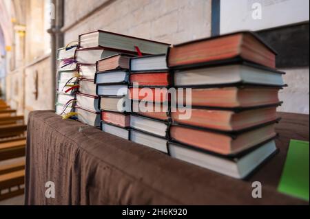 Stapel von Bibeln und Hymnenbüchern auf einem Tisch in einer Kirche oder Kathedrale. Stockfoto