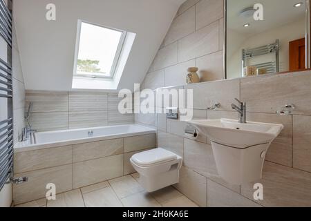 Essex, England - November 18 2019: Modernes, gefliestes Badezimmer-wc mit keramischen Wandwaschbecken, Handtuchhalter und Spiegel. Stockfoto