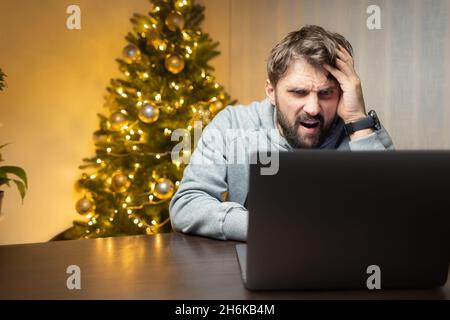 Müde Arbeiter, sitzt ein Mann vor einem Laptop in der Weihnachtsnacht Stockfoto
