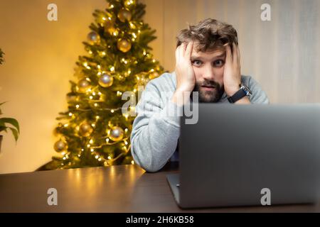 Müde Arbeiter, sitzt ein Mann vor einem Laptop in der Weihnachtsnacht Stockfoto