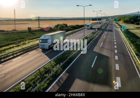 Drei Transporter, die auf einer Landstraße oder Autobahn vorbeifahren. Business Transport und Trucking Industrie. Stockfoto