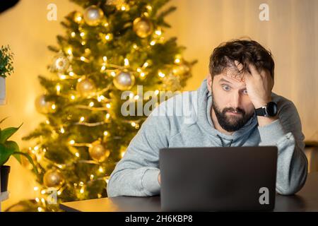 Ein enttäuschter Mann sitzt am Silvesterabend im Büro vor einem Computer Stockfoto