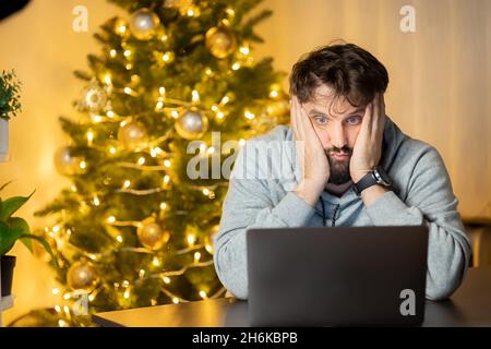 Ein enttäuschter Mann sitzt am Silvesterabend im Büro vor einem Computer Stockfoto