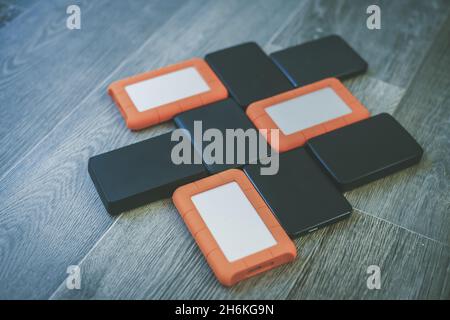 Viele tragbare Festplatten auf dem Holzboden. Mosaik von usb-Speichergeräten. Externe Computergeräte. Cloud-Technologie, Online-Festplatte, Remote-Back-U Stockfoto