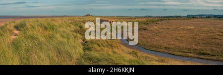 Panoramablick auf eine alte Pillendose aus dem Zweiten Weltkrieg zwischen den Dünen neben Salzmarschen am Brancaster Beach North Norfolk England Stockfoto