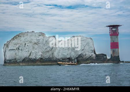 Die Nadeln und der Leuchtturm auf der Solent auf der Isle of Wight Hampshire England mit einem gelben Tour-Schnellboot, das vorbeifährt Stockfoto