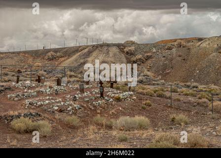 Tonopah, Nevada, USA - 18. Mai 2011: Historischer Friedhof. Auf dem braunen, trockenen Wüstenboden sammeln sich dicke, graue Sturmwolken über dem Friedhof. Zäune trennen sich von i Stockfoto