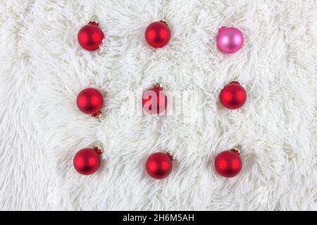 Weihnachts- und Neujahrskonzept. Weihnachtskugeln auf weißem Kunstpelzhintergrund. Flauschiger Hintergrund. Flach liegend. Speicherplatz kopieren. Stockfoto