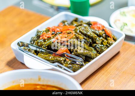 Türkisch und arabisch traditionell Ramadan Essen gefüllte Traubenblätter mit Reis und Fleisch, Sarma mit Tomatenscheiben auf einem weißen Teller. Sarma ist ein Gericht aus Trauben. Platz für Textbereich kopieren. Hochwertige Fotos Stockfoto