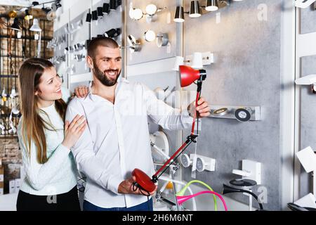 Positive Familie Kauf versucht Tischleuchte im modernen Möbelgeschäft Stockfoto