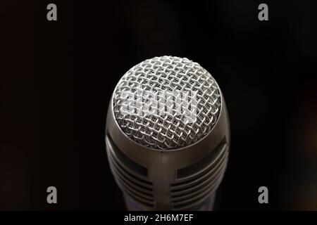 Professionelles Mikrofon in einem Musikstudio auf schwarzem Hintergrund. Aufnehmen von Geräuschen und Liedern. Chrom-Metall-Mikrofon. Digitalrekorder und -Technologie. Stockfoto