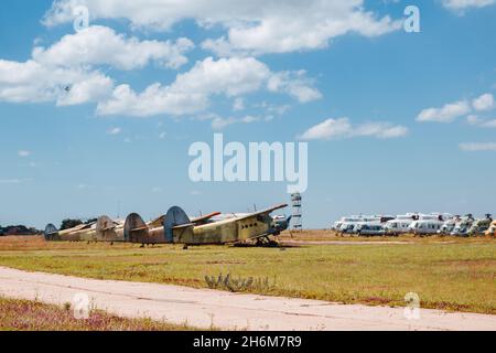 Alte zerstörte verlassene Flugzeuge und Hubschrauber auf dem Feld, Friedhof von alten Hubschraubern und Flugzeugen. Stockfoto