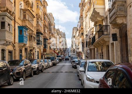 Traditionelle farbenfrohe Gebäude in der Republic Street in Valletta, Malta. Autos auf der Straßenseite geparkt. UNESCO-Weltkulturerbe Stockfoto