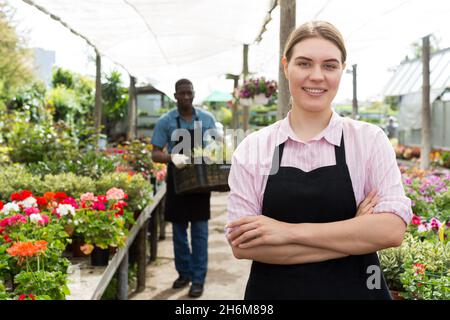 Weibliche Arbeiterin, die Blumen im Gewächshaus überprüft Stockfoto