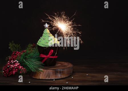 Weihnachtskuchen mit Sparkler, festlicher Muffin mit Buttercreme auf dunklem Holzhintergrund, Kopierraum. Stockfoto