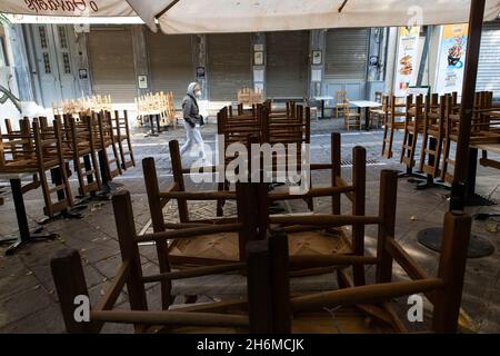Athen, Griechenland. November 2021. Am 16. November 2021 läuft ein Fußgänger an einem geschlossenen Restaurant in Athen, Griechenland, vorbei. Restaurants und Cafés in ganz Griechenland blieben am Dienstag geschlossen, während in Athen eine Demonstration stattfand, in der weitere staatliche Unterstützung im Rahmen der neuen COVID-19-Beschränkungen gefordert wurde, die von der Regierung im Herbst dieses Jahres eingeführt wurden, um den jüngsten Anstieg der Infektionsraten zu bekämpfen. Quelle: Marios Lolos/Xinhua/Alamy Live News Stockfoto