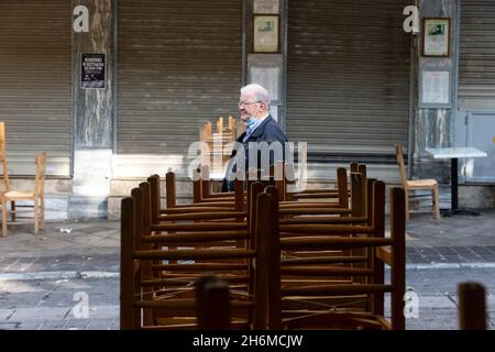 Athen, Griechenland. November 2021. Ein Mann geht am 16. November 2021 an einem geschlossenen Restaurant in Athen, Griechenland, vorbei. Restaurants und Cafés in ganz Griechenland blieben am Dienstag geschlossen, während in Athen eine Demonstration stattfand, in der weitere staatliche Unterstützung im Rahmen der neuen COVID-19-Beschränkungen gefordert wurde, die von der Regierung im Herbst dieses Jahres eingeführt wurden, um den jüngsten Anstieg der Infektionsraten zu bekämpfen. Quelle: Marios Lolos/Xinhua/Alamy Live News Stockfoto