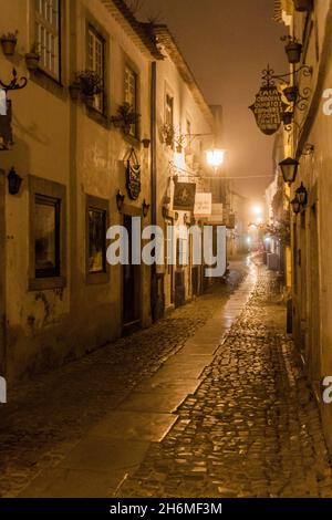 OBIDOS, PORTUGAL - 11. OKTOBER 2017: Nachtansicht einer engen gepflasterten Straße im Dorf Obidos, Portugal Stockfoto