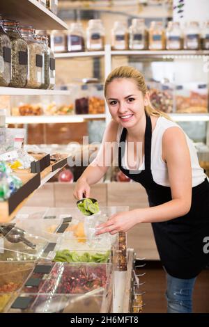 Junge Frau, die mit getrockneten Beeren steht, verkauft Stockfoto
