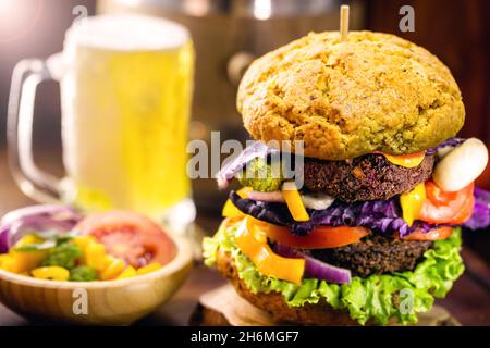 Veganer Burger auf Vollkornbrot mit kaltem Bier im Hintergrund. Vegetarischer Snack ohne Fleisch und ohne Milchprodukt, ohne Eier. Stockfoto