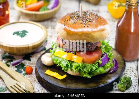 Veganer Burger auf Vollkornbrot, hausgemachtes Brot, hergestellt mit schwarzen Bohnen, Gemüse, Pilzen, weißer Kastaniencreme, Senf. Gesunder Snack Stockfoto