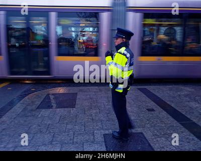 DUBLIN, IRLAND - 17. Dezember 2019: Selektiver Fokus auf einen irischen Polizeibeamten (Garda Siochana), der den Verkehr im Stadtzentrum von Dublin kontrolliert. In Bewegung Stockfoto