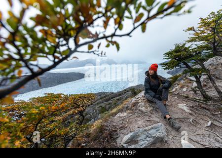 Eine junge Frau sitzt auf dem Felsen mit Grey Glacier im Hintergrund, Torres del Paine National Park, Chile Stockfoto