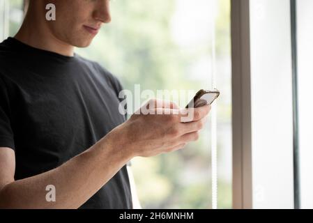 Nahaufnahme eines lächelnden jungen Mannes mit Smartphone Stockfoto