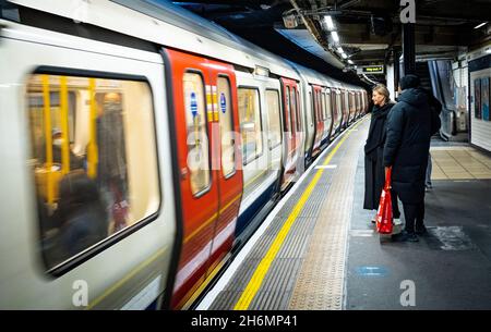 Eine Frau wartet mit ihrem männlichen Begleiter auf eine Londoner U-Bahn, die am 14. November 2021 an der U-Bahn-Station Westminster anhält und ihre Türen öffnet. Stockfoto