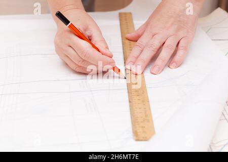 Weibliche Hände machen das Layout des Nähmusters auf Papier Stockfoto
