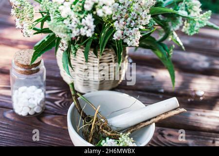 Baldrian-Tabletten mit beruhigenden Eigenschaften. Pharmazeutisches Glas mit Pillen auf einem Holztisch. Kochen Baldrianwurzel in einem Mörser für Kräuterelixiere. S Stockfoto